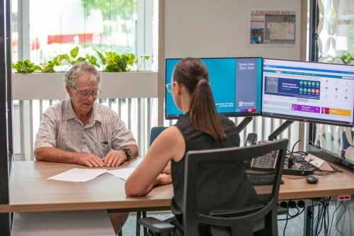 A Housing Officer helps an elderly customer.