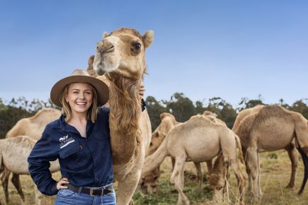 A Qcamel staff member smiles at us while patting a camel.