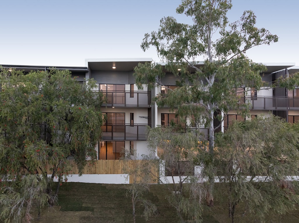 External side view, showing all 3 levels behind native trees on the adjacent site.
