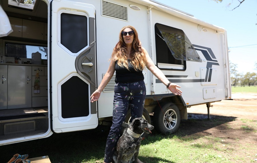 Photo of Lyteesha and her dog in front of her white caravan in Tara