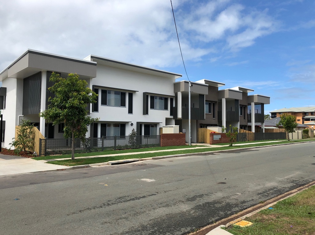 View from the street. Small scale, with a small-scale, townhouse appearance. The building is painted in neutral colours with feature front fencing. 